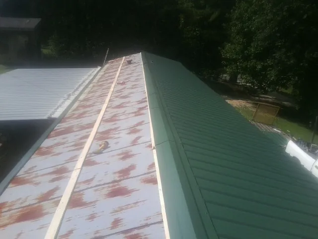 Old rusted panels beside newly installed green metal roofing — Wind Damage Roof Repair by Roofing Brothers in Sumner